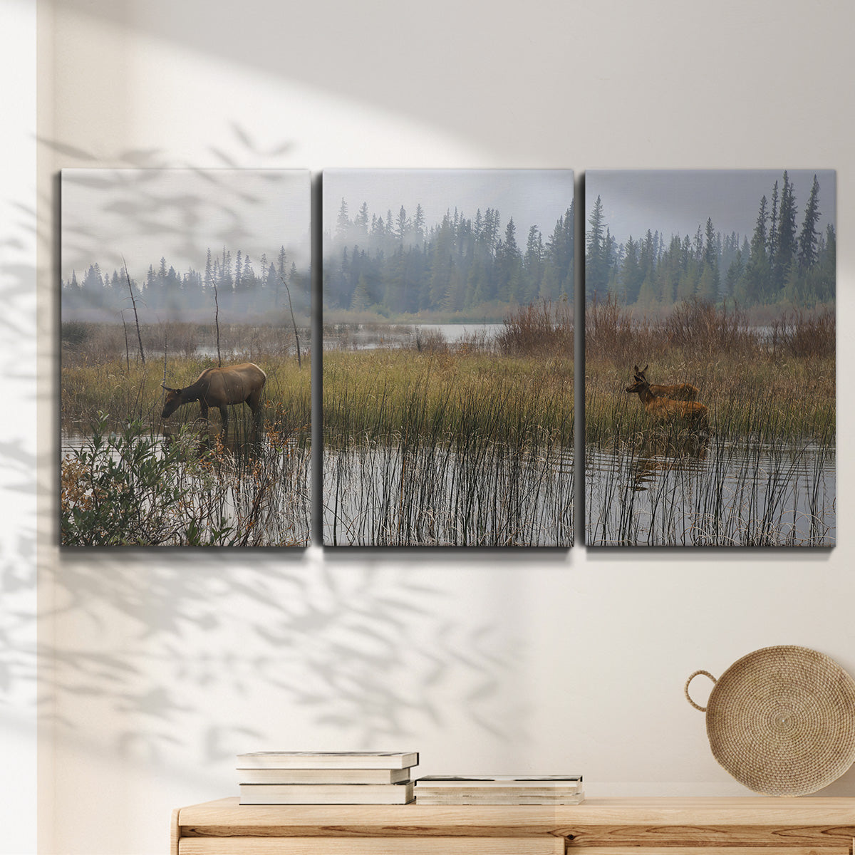 Three-panel canvas wall art featuring wildlife walking through open field, displayed in a minimalist living room above a console table.