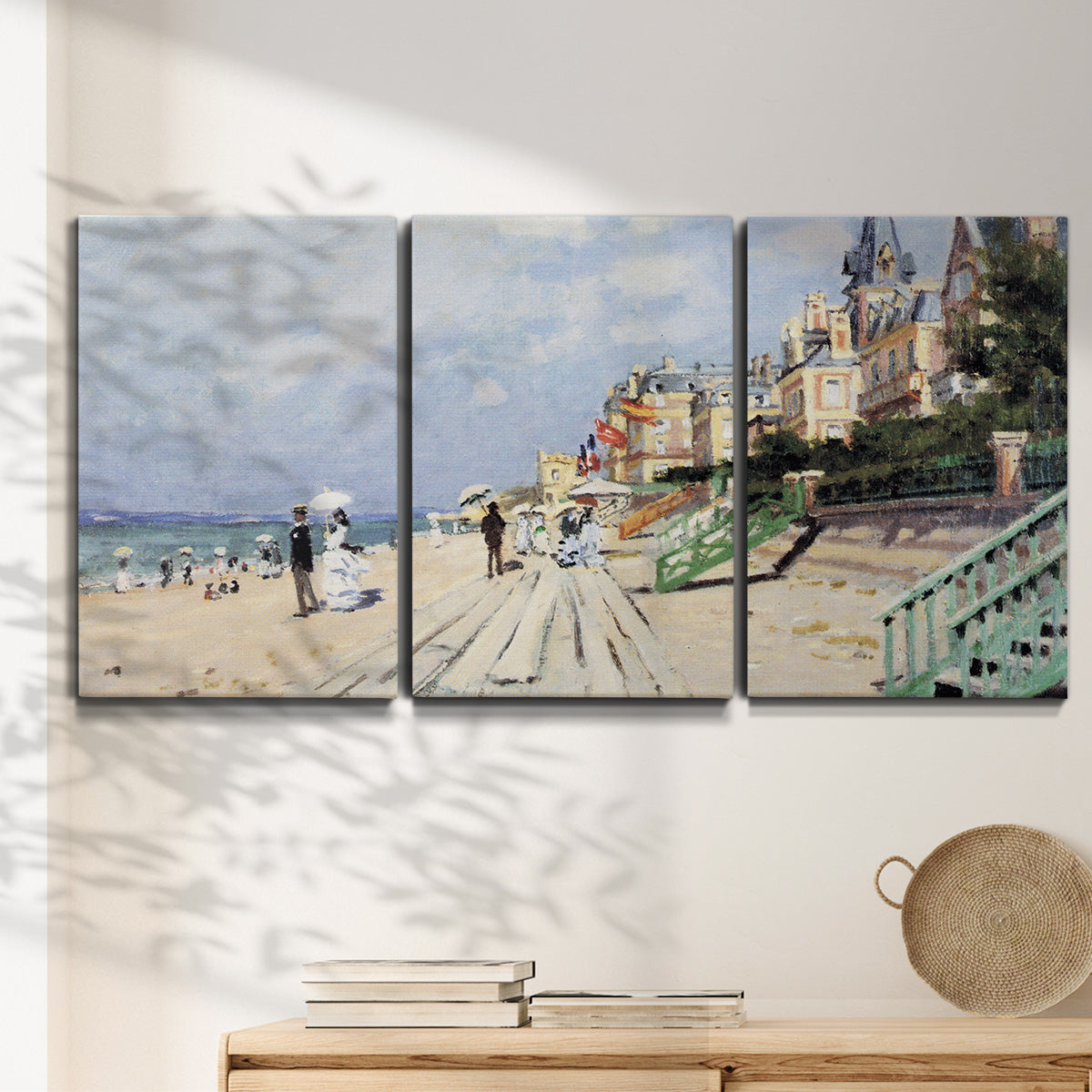 Three-panel canvas wall art featuring figures strolling along beach, displayed in a minimalist living room above a console table.