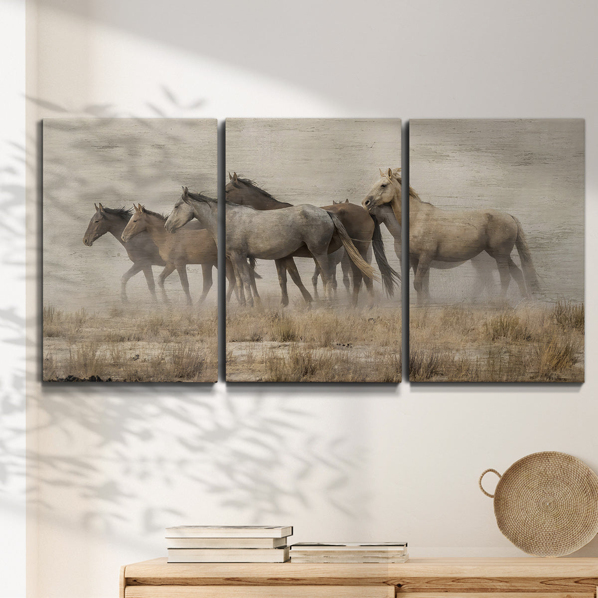 Three-panel canvas wall art featuring wild horses roaming open terrain, displayed in a minimalist living room above a console table.