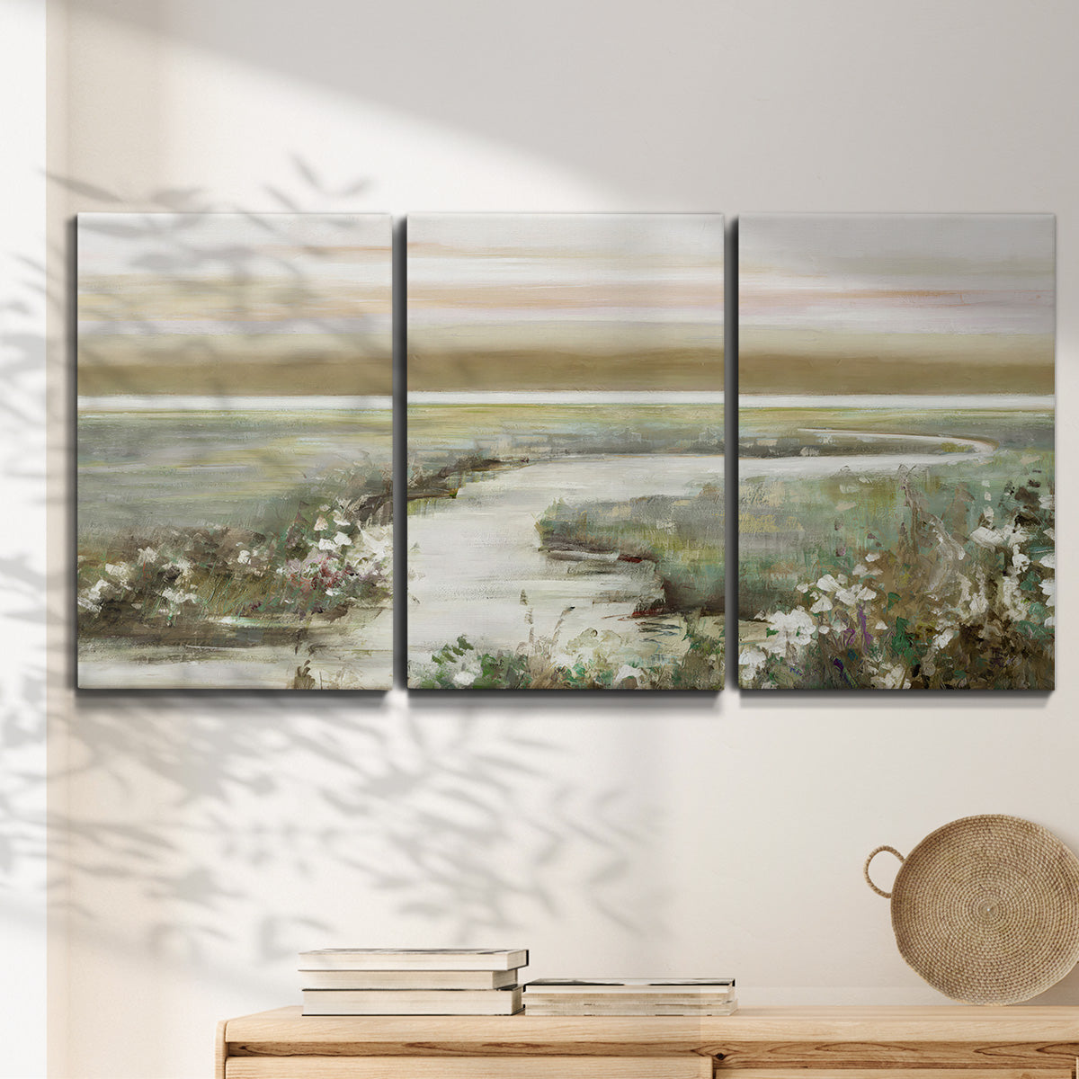 Three-panel canvas wall art featuring pastoral fields under soft sunrise, displayed in a minimalist living room above a console table.