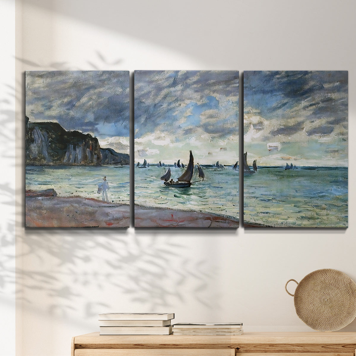 Three-panel canvas wall art featuring figures walking along sandy shoreline, displayed in a minimalist living room above a console table.