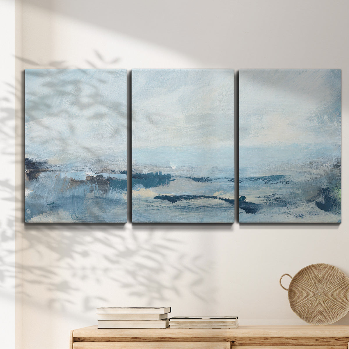 Three-panel canvas wall art featuring abstract sailboats on water, displayed in a minimalist living room above a console table.