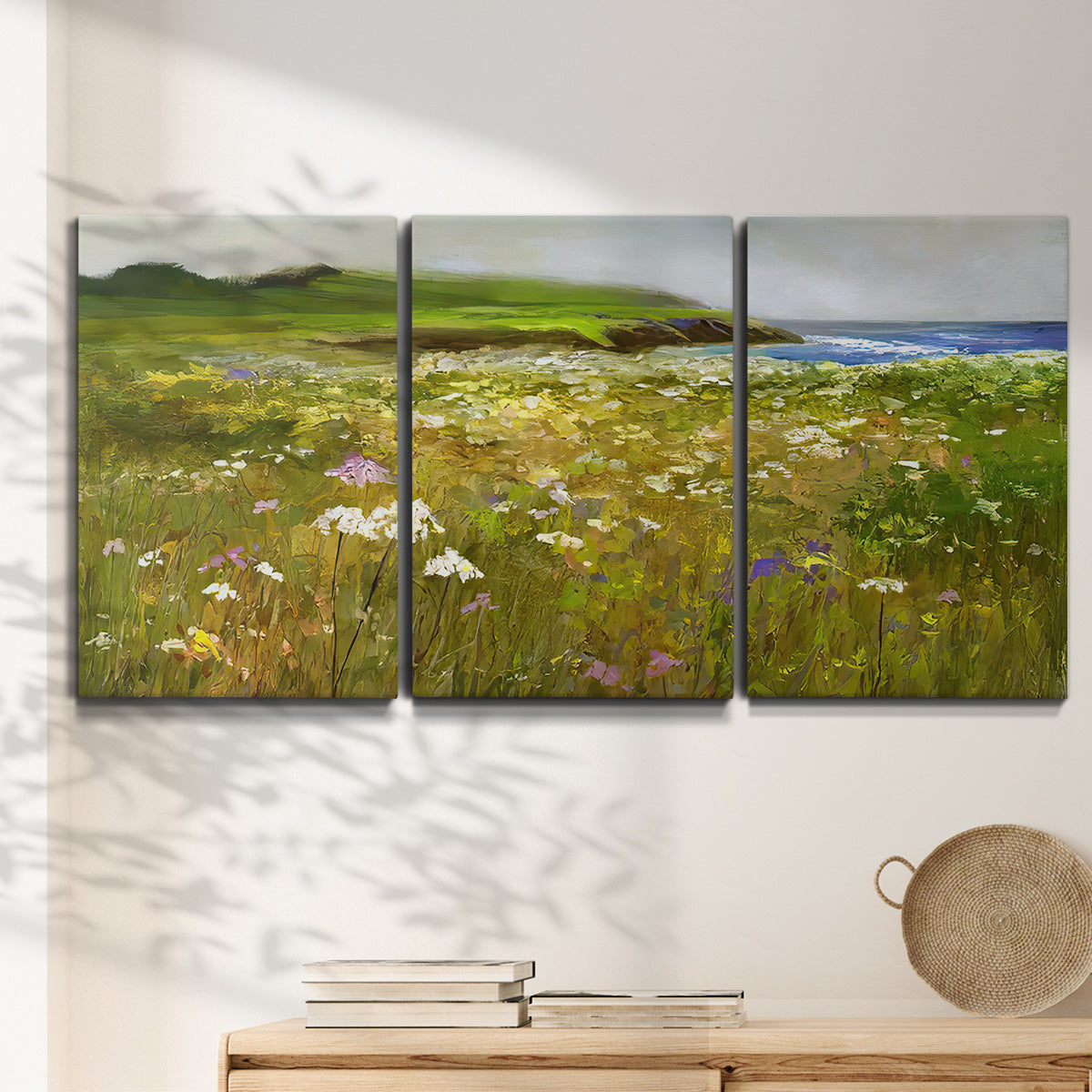 Three-panel canvas wall art featuring rugged coastal cliff landscape, displayed in a minimalist living room above a console table.