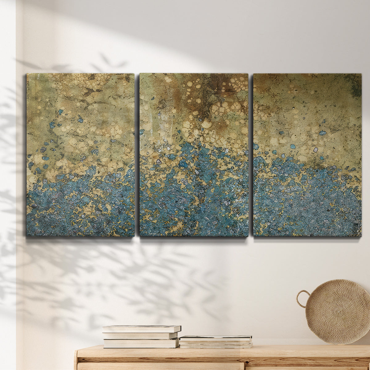 Three-panel canvas wall art featuring metallic abstract gold tones, displayed in a minimalist living room above a console table.