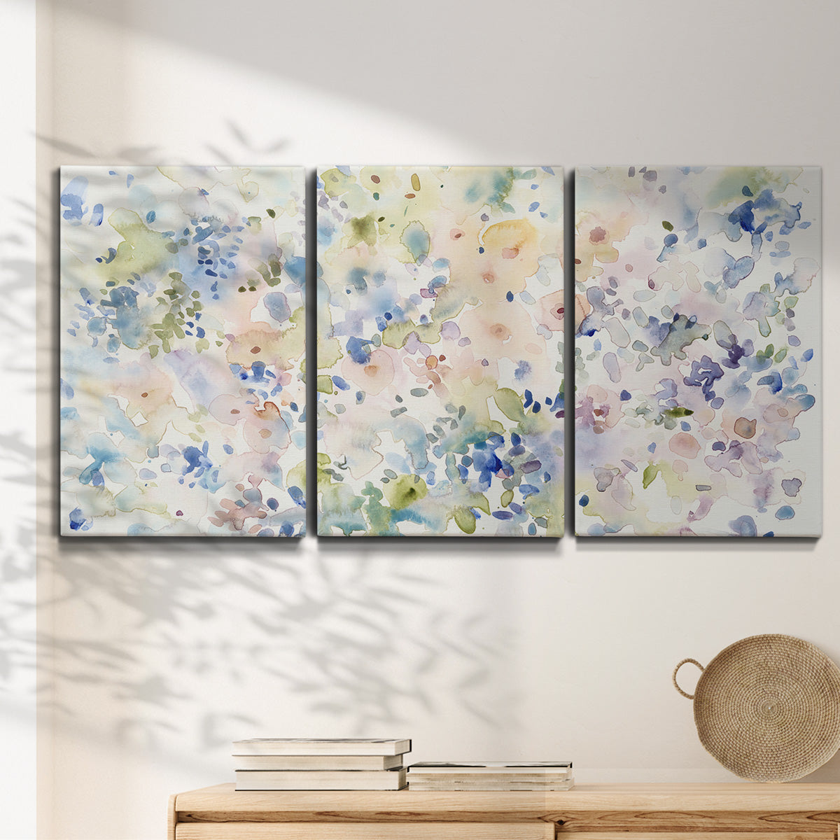 Three-panel canvas wall art featuring flowing abstract watercolor, displayed in a minimalist living room above a console table.