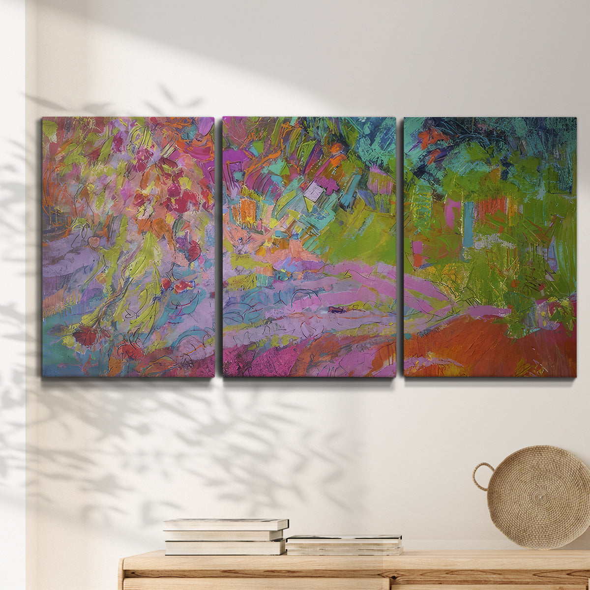 Three-panel canvas wall art featuring vibrant abstract with dramatic motion, displayed in a minimalist living room above a console table.