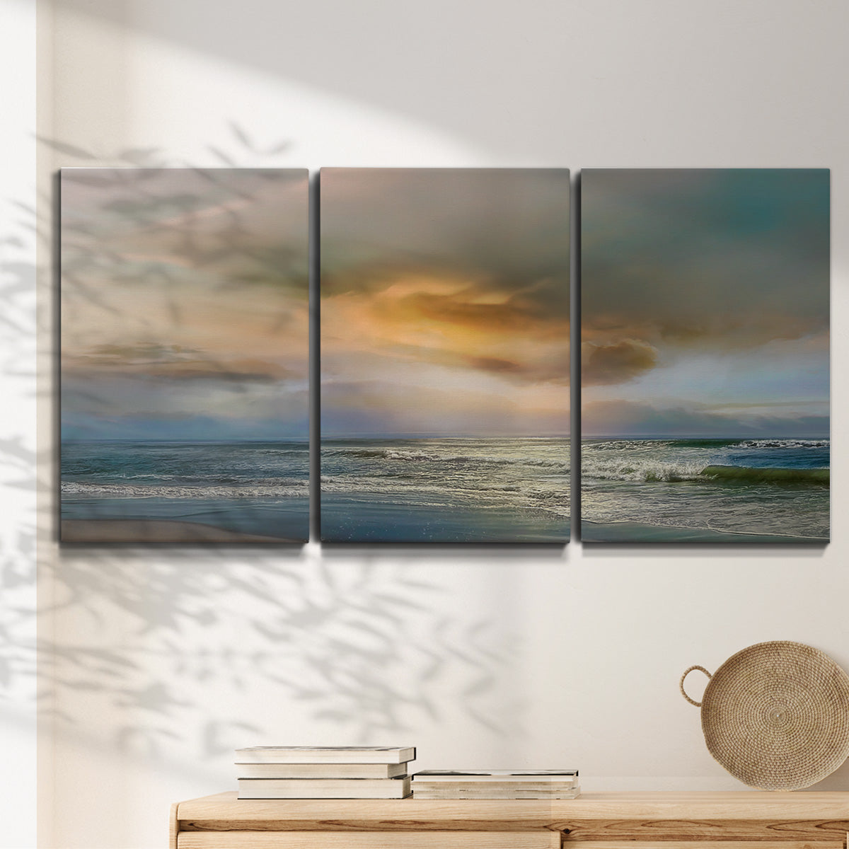 Three-panel canvas wall art featuring tranquil beach at sunset, displayed in a minimalist living room above a console table.