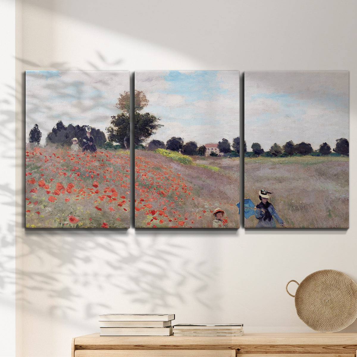 Three-panel canvas wall art featuring poppy field stretching across meadow, displayed in a minimalist living room above a console table.
