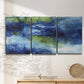 Three-panel canvas wall art featuring flowing blue abstract watercolor, displayed in a minimalist living room above a console table.