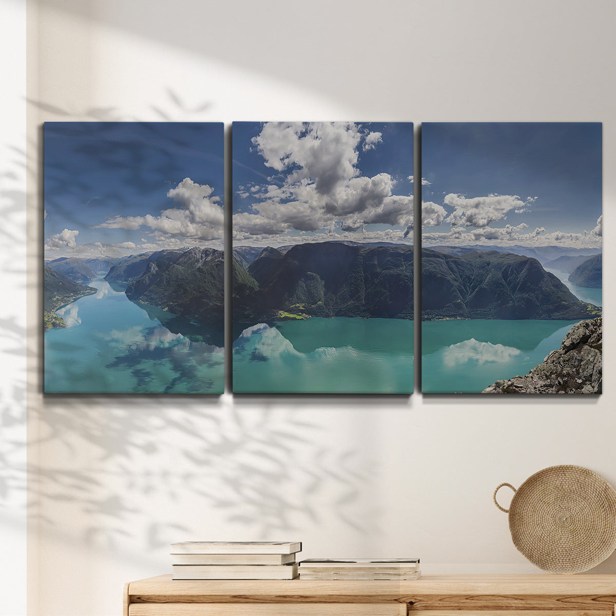 Three-panel canvas wall art featuring tropical water reflections with foliage, displayed in a minimalist living room above a console table.
