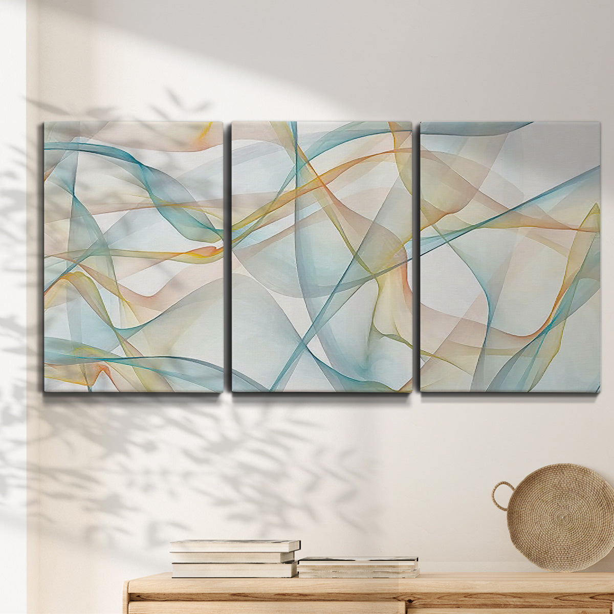 Three-panel canvas wall art featuring flowing abstract curves and wave patterns, displayed in a minimalist living room above a console table.