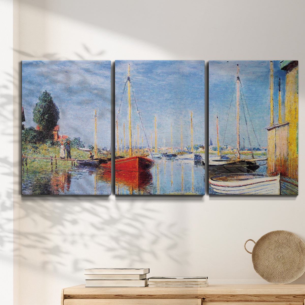 Three-panel canvas wall art featuring sailboats gathered along river, displayed in a minimalist living room above a console table.