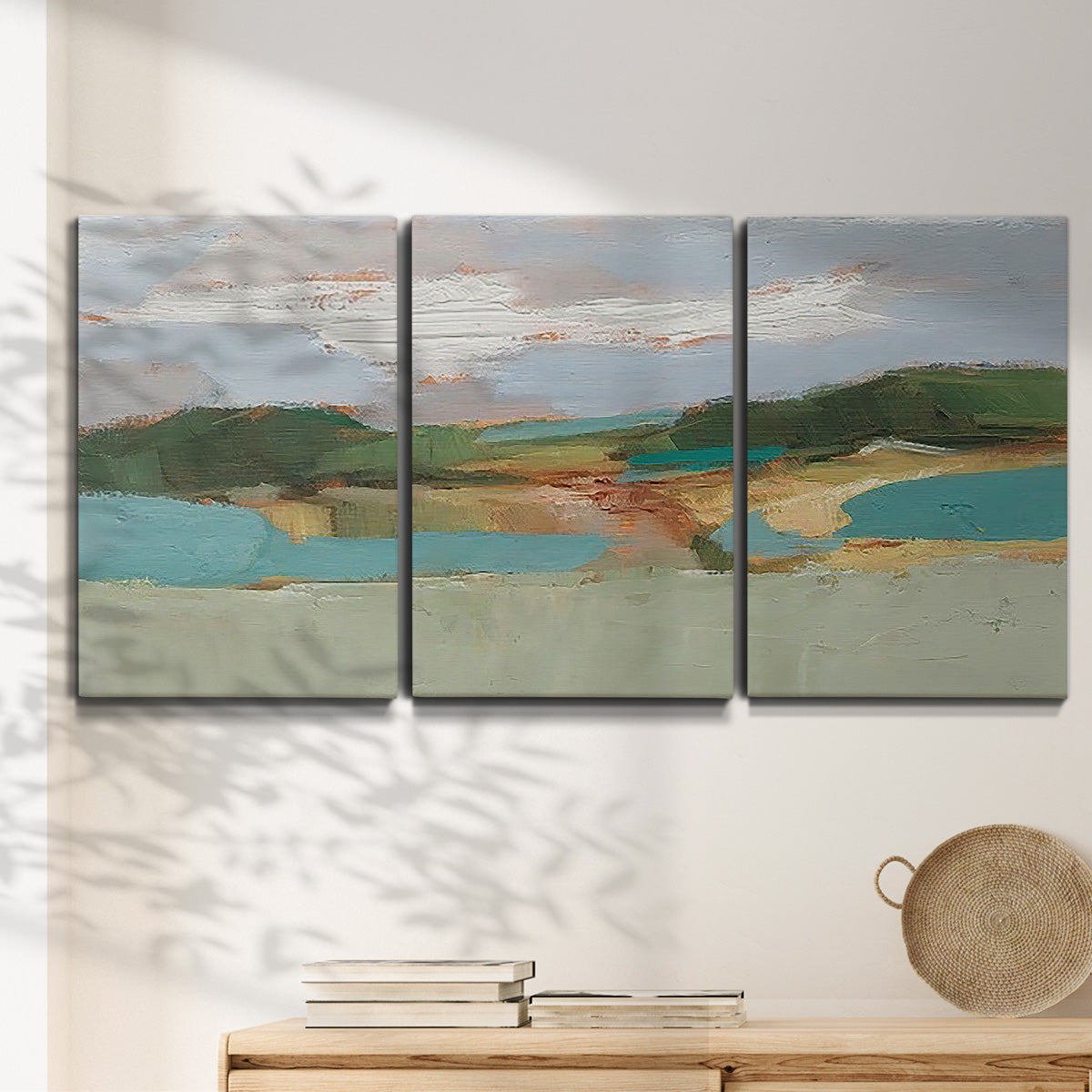 Three-panel canvas wall art featuring wide open landscape under midday light, displayed in a minimalist living room above a console table.