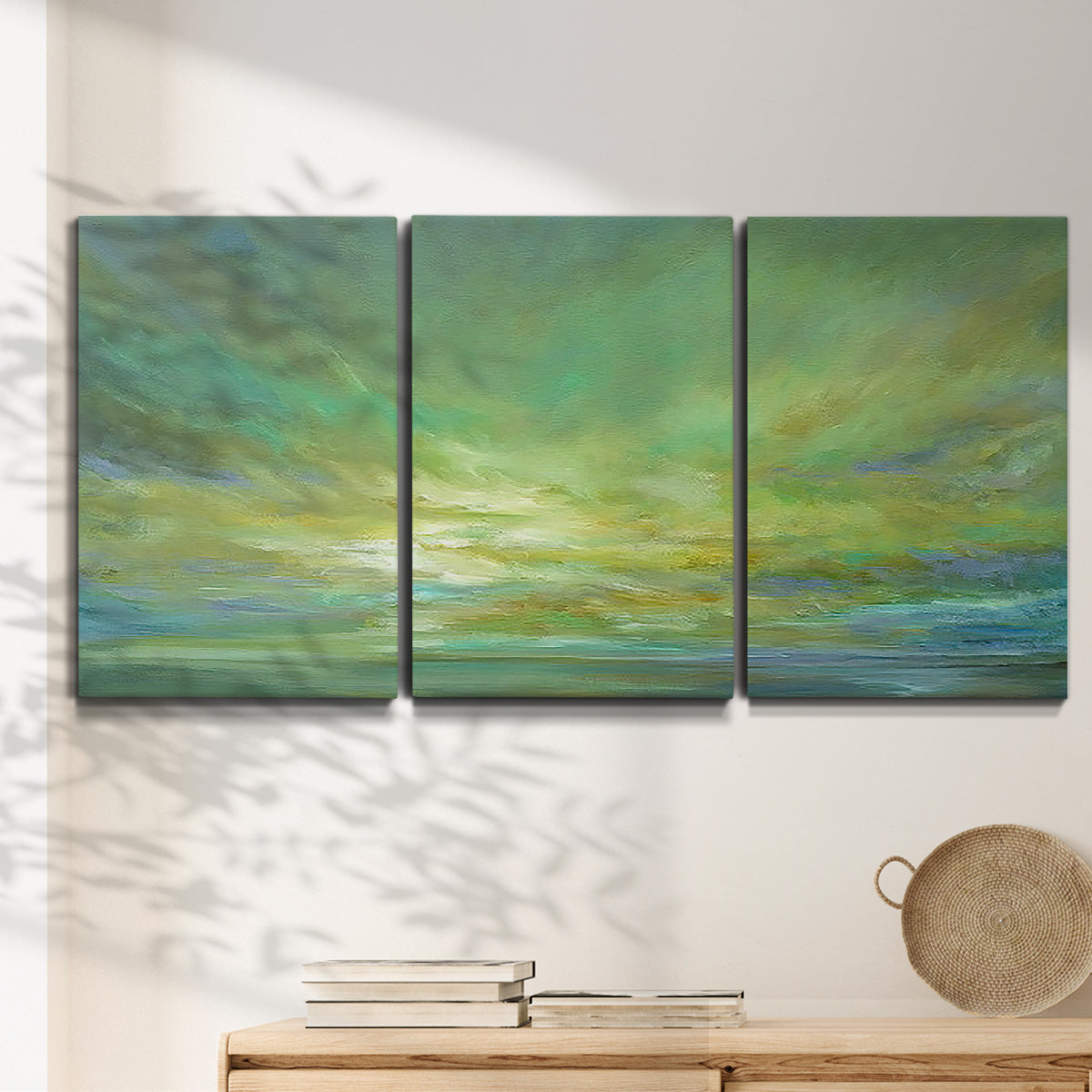 Three-panel canvas wall art featuring coastal shoreline under open sky, displayed in a minimalist living room above a console table.