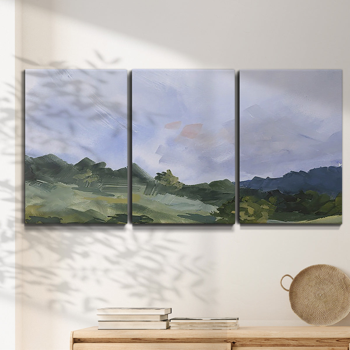 Three-panel canvas wall art featuring wide open pastoral horizon landscape, displayed in a minimalist living room above a console table.
