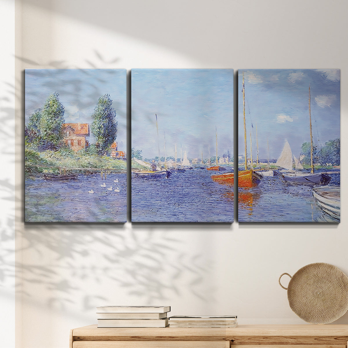 Three-panel canvas wall art featuring river flowing past riverside town, displayed in a minimalist living room above a console table.