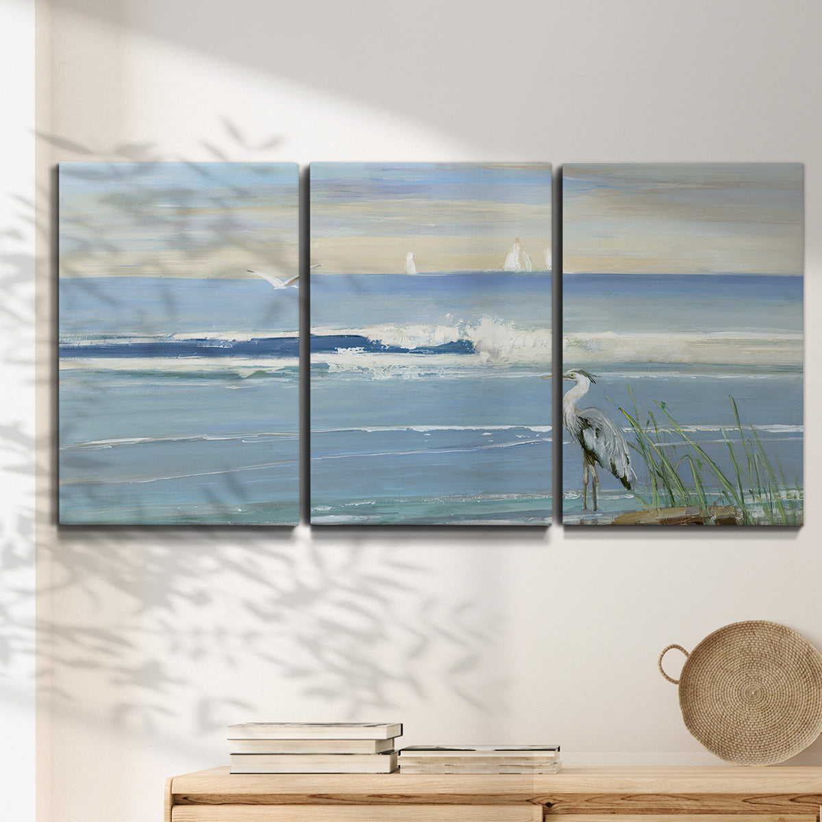Three-panel canvas wall art featuring sunrise reflecting across bay waters, displayed in a minimalist living room above a console table.