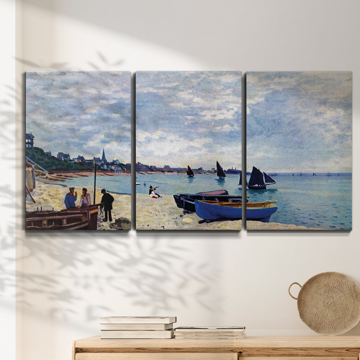 Three-panel canvas wall art featuring busy beach scene with shoreline, displayed in a minimalist living room above a console table.