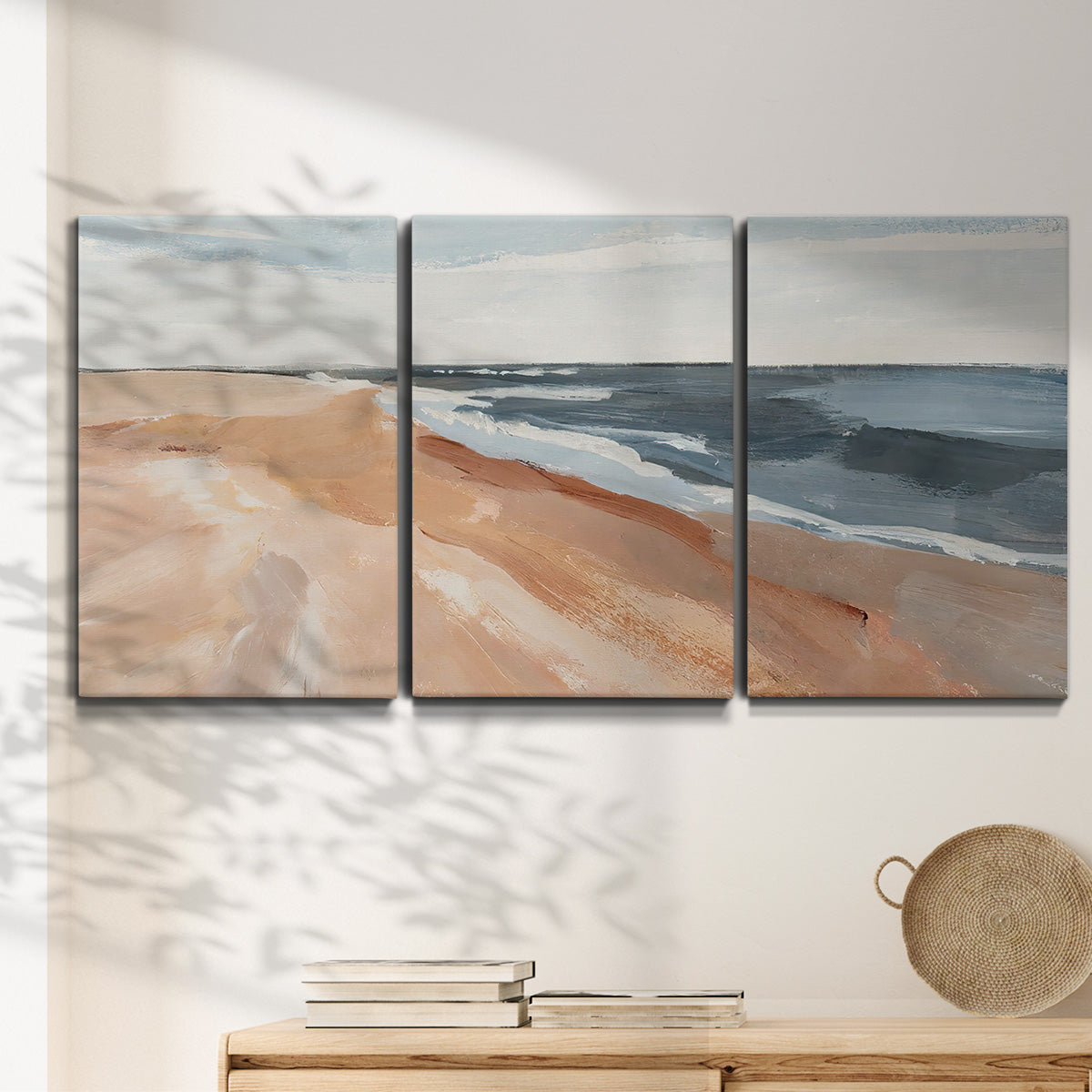 Three-panel canvas wall art featuring abstract coastal beach composition, displayed in a minimalist living room above a console table.