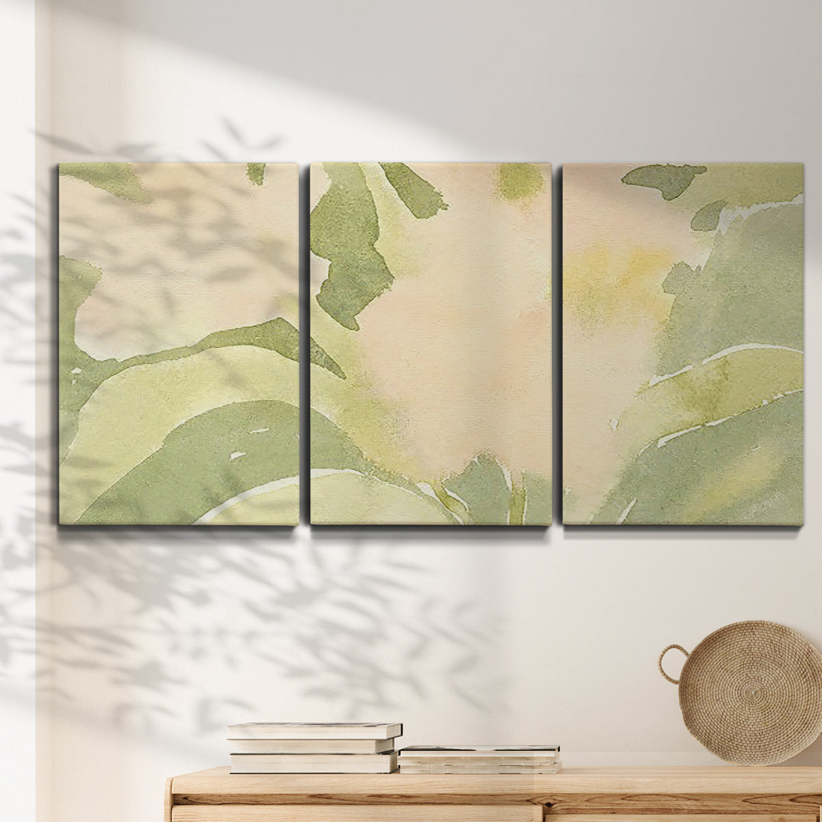 Three-panel canvas wall art featuring minimal verdant floral abstraction, displayed in a minimalist living room above a console table.