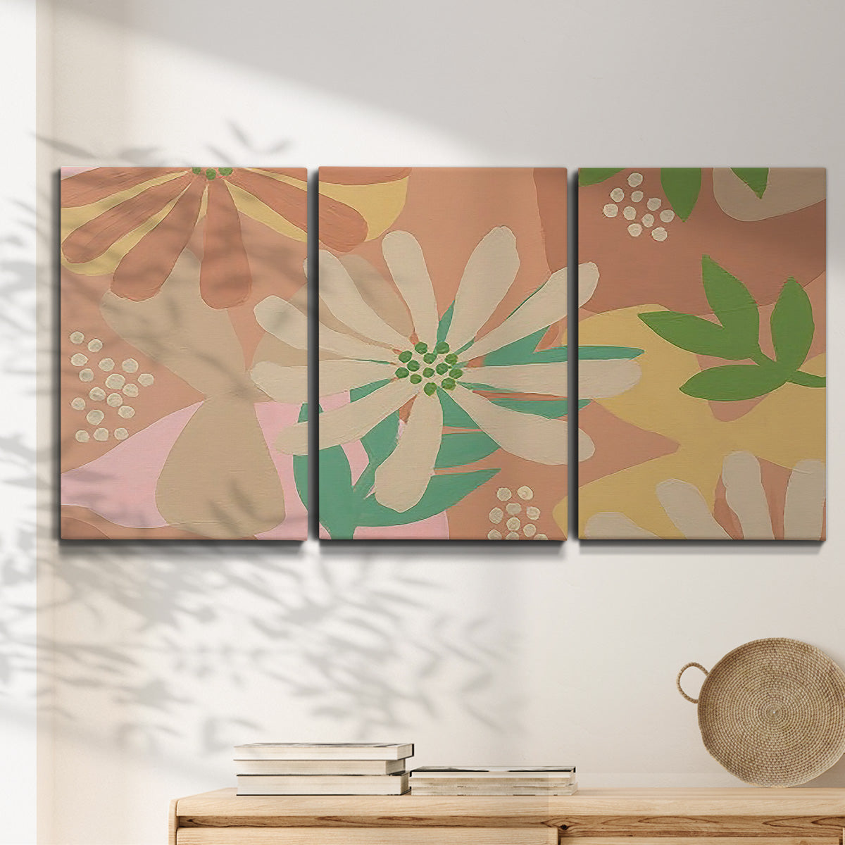 Three-panel canvas wall art featuring neutral toned botanical floral silhouettes, displayed in a minimalist living room above a console table.