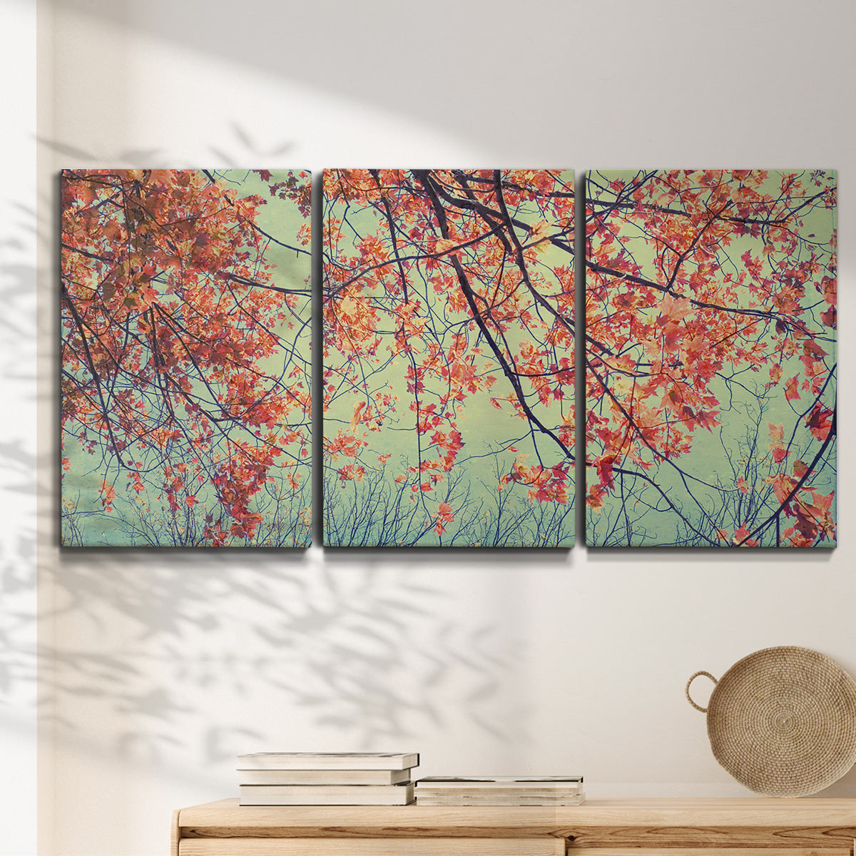 Three-panel canvas wall art featuring autumn foliage landscape photograph, displayed in a minimalist living room above a console table.