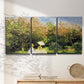 Three-panel canvas wall art featuring lush garden landscape with trees, displayed in a minimalist living room above a console table.