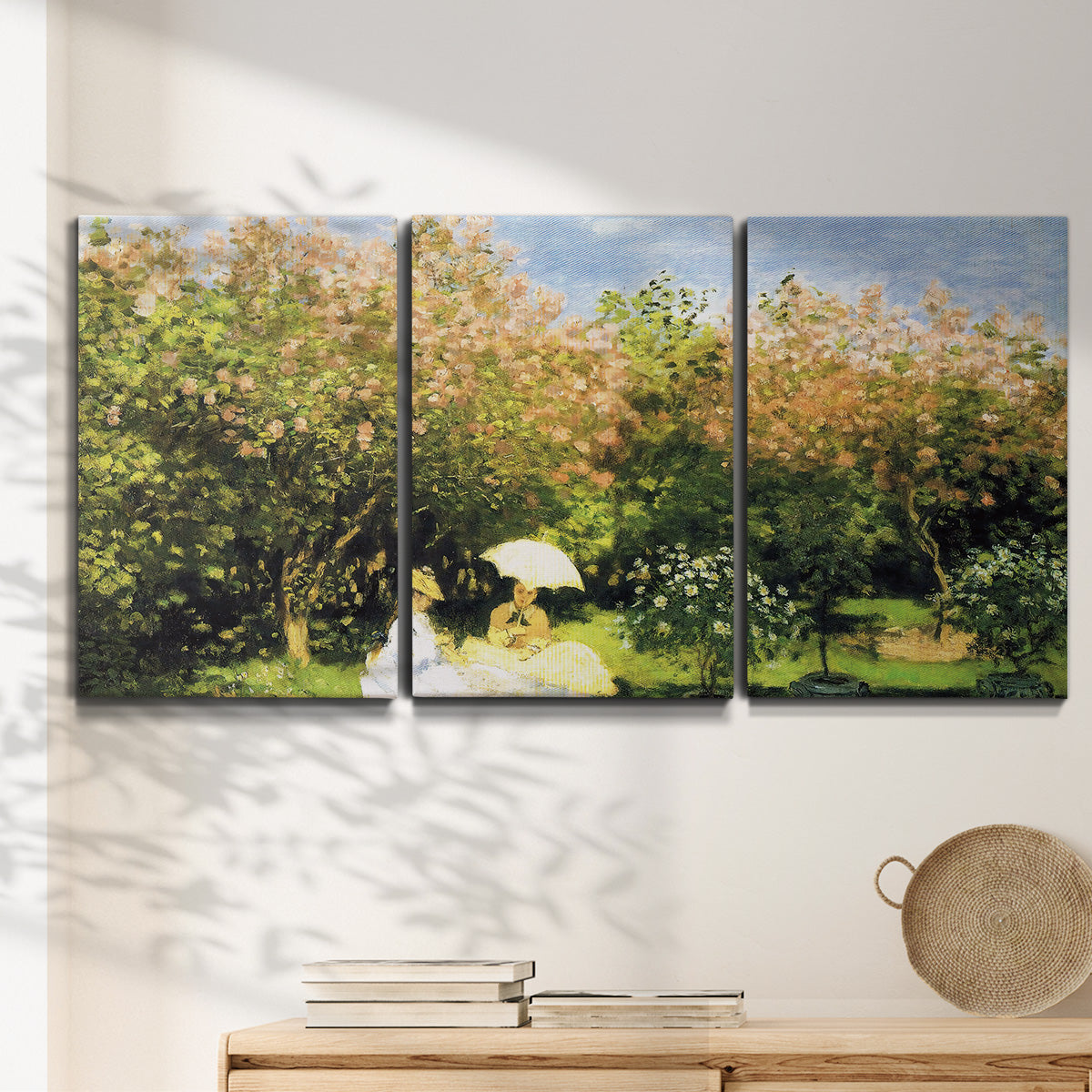 Three-panel canvas wall art featuring lush garden landscape with trees, displayed in a minimalist living room above a console table.