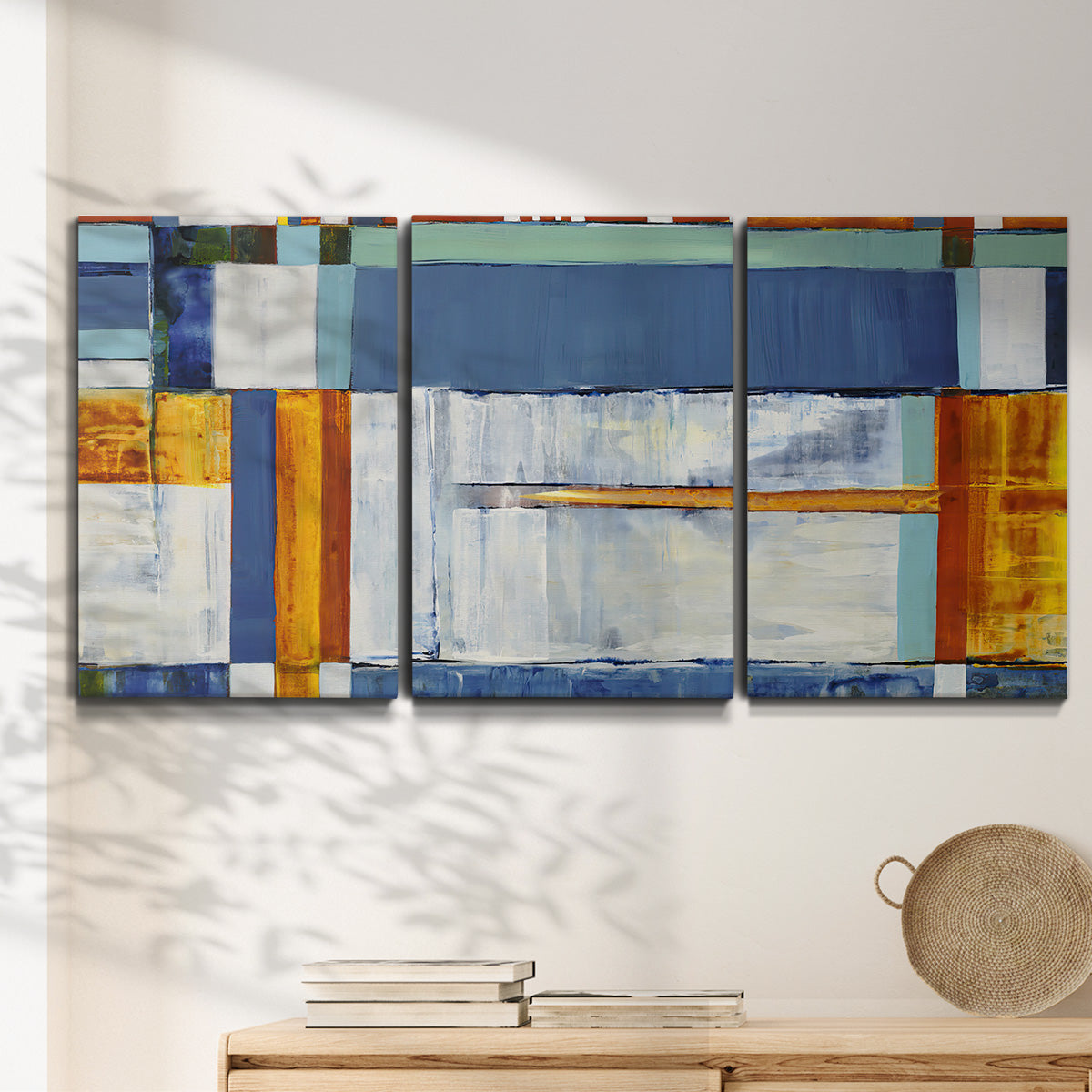 Three-panel canvas wall art featuring bright mid century geometric abstraction, displayed in a minimalist living room above a console table.