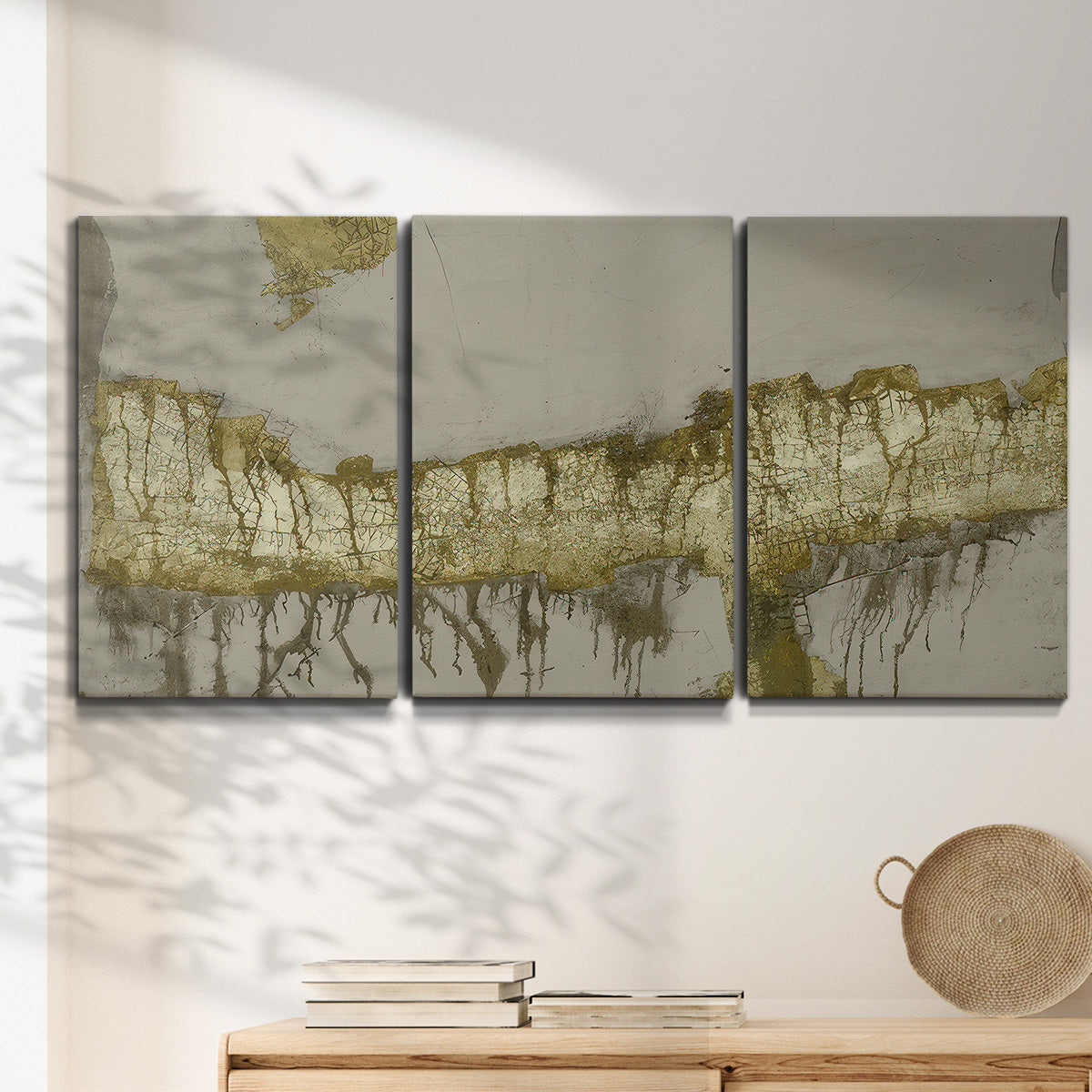 Three-panel canvas wall art featuring gold accented abstract ravine, displayed in a minimalist living room above a console table.