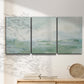Three-panel canvas wall art featuring soft abstract coastal tones, displayed in a minimalist living room above a console table.
