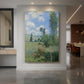 Canvas art print of an impressionist landscape of a village with soft light and natural tones displayed as a statement piece in a spacious interior.