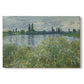 Canvas art print portraying a riverbank landscape with water, trees, and distant village buildings, set against a white background