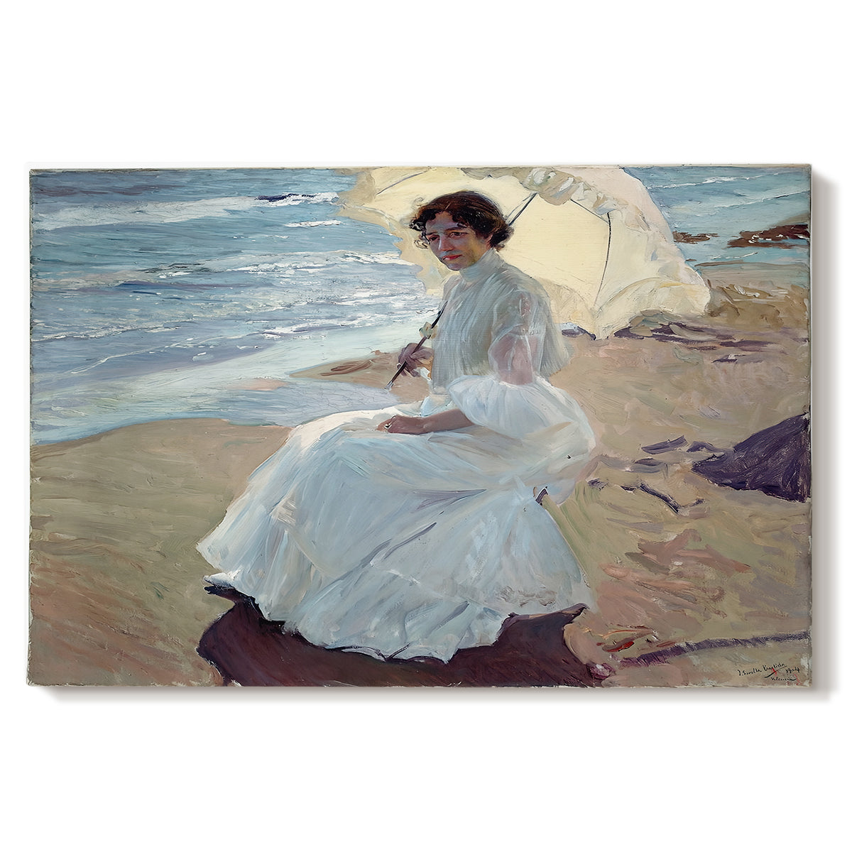 Canvas art print portraying a woman seated on beach in flowing white dress beside water, set against a white background