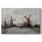 Canvas art print portraying windmills standing beside water under open sky in rural landscape, set against a white background