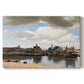 Canvas art print portraying a cityscape of Delft with buildings reflected in calm water, set against a white background