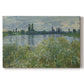Canvas art print portraying a riverbank landscape with water, trees, and distant village buildings, set against a white background