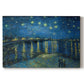 Canvas art print portraying a night scene with glowing stars reflected in river beside illuminated town, set against a white background