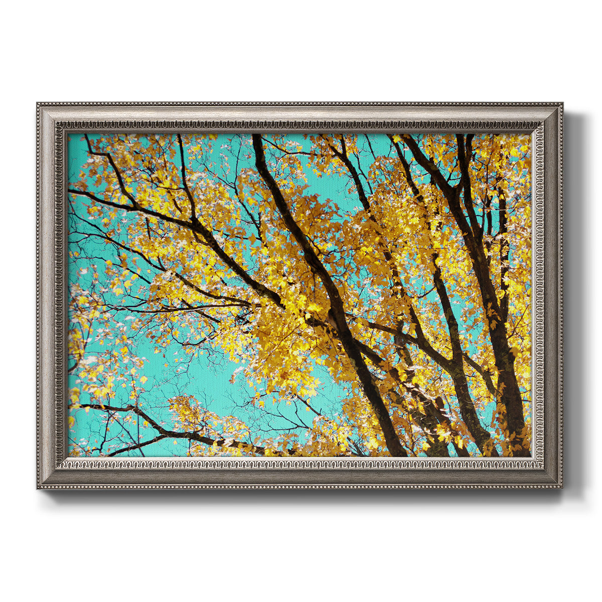 Bright autumn leaves against a blue sky printed on canvas in an ornate vintage silver frame.