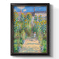 Impressionist garden landscape painting by Claude Monet printed on canvas in an ornate black frame with gilded inner detail with a vertical orientation.