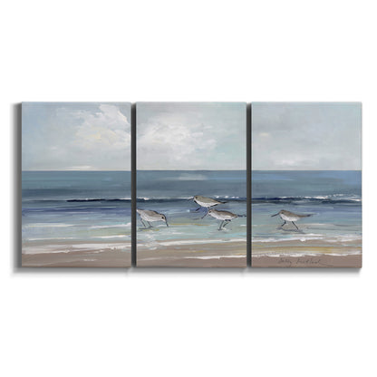 Three-panel canvas wall art featuring shore birds searching along beach on white background.