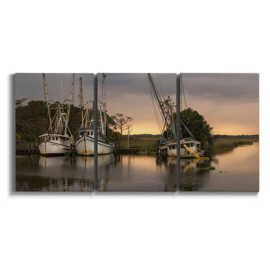 Three-panel canvas wall art featuring fishing trawlers on working harbor on white background.