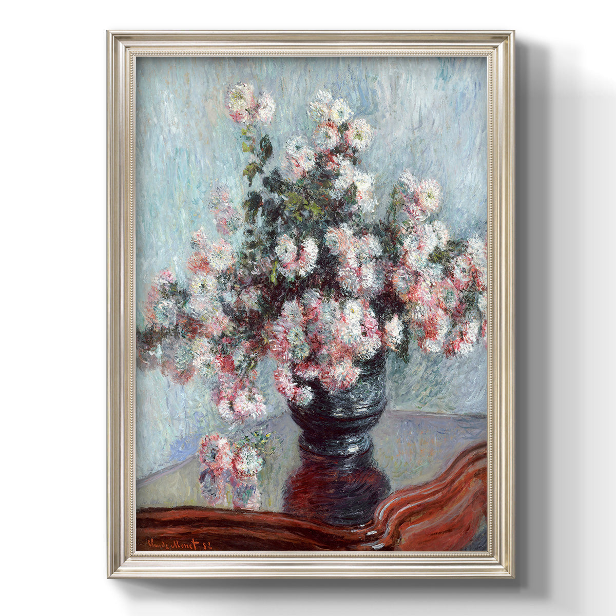 Impressionist chrysanthemum floral painting by Claude Monet printed on canvas in an ornate black frame with gilded inner detail with a vertical orientation.