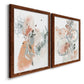 Angled view of a set of two maple barnwood framed canvas prints featuring two abstract watercolor botanicals featuring loose blush gray and coral floral gestures.