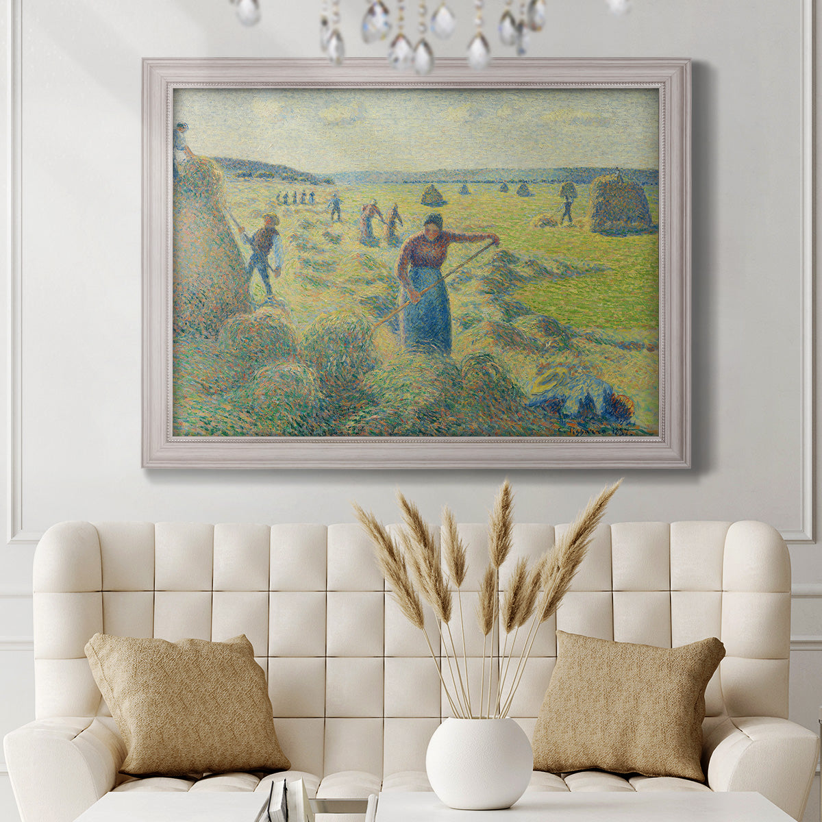 Impressionist rural hay harvest landscape by Camille Pissarro in an ornate weathered white frame displayed in a neutral-toned interior setting.