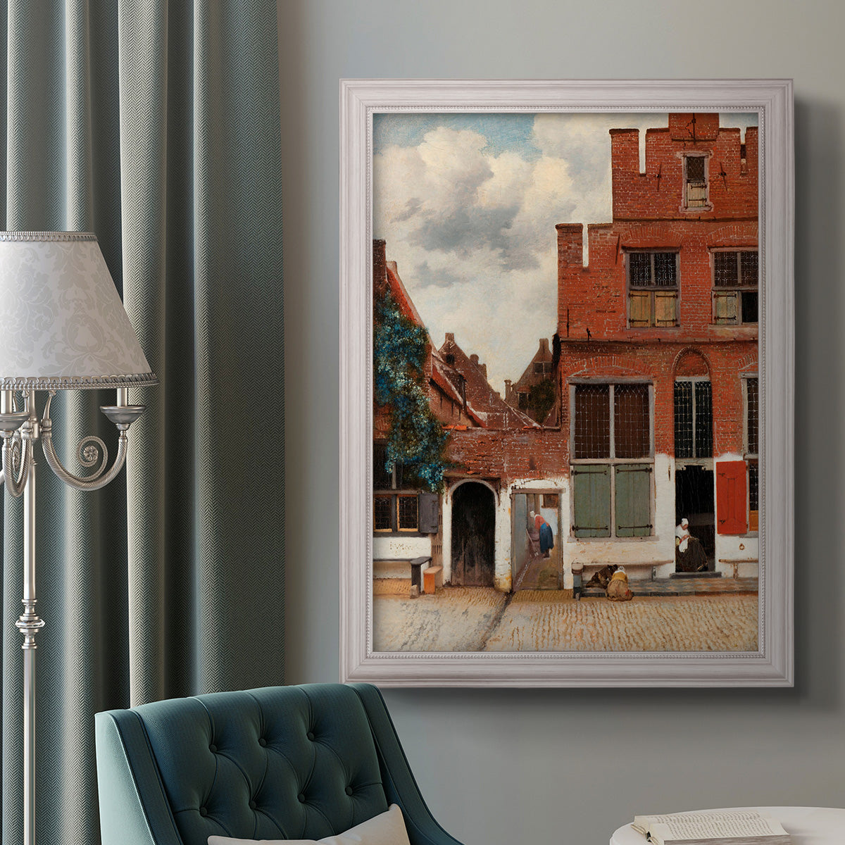 Realist city street scene by Johannes Vermeer in an ornate weathered white frame displayed in a neutral interior setting.