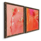 Angled view of a set of two walnut barnwood framed canvas prints featuring two glamorous fluid abstracts featuring luminous coral orange and pink color fields with gold flecks.