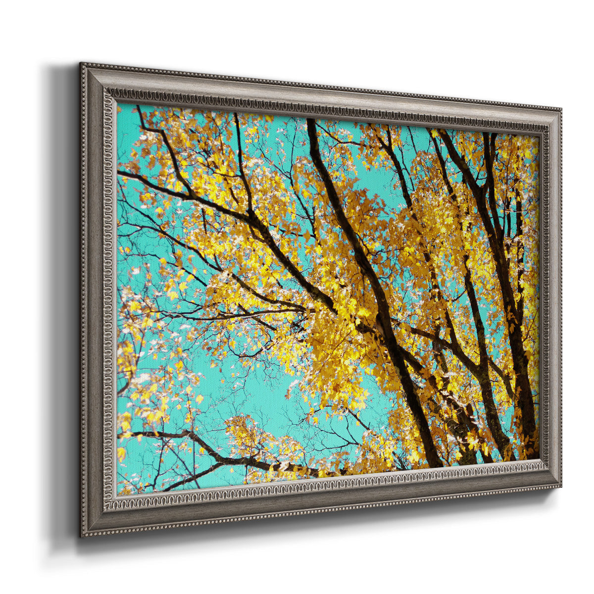 Bright autumn leaves against a blue sky printed on canvas in an ornate vintage silver frame.
