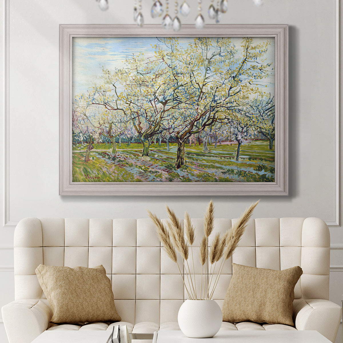 Impressionist white-blossomed orchard landscape by Vincent van Gogh in an ornate weathered white frame displayed in a neutral-toned interior setting.