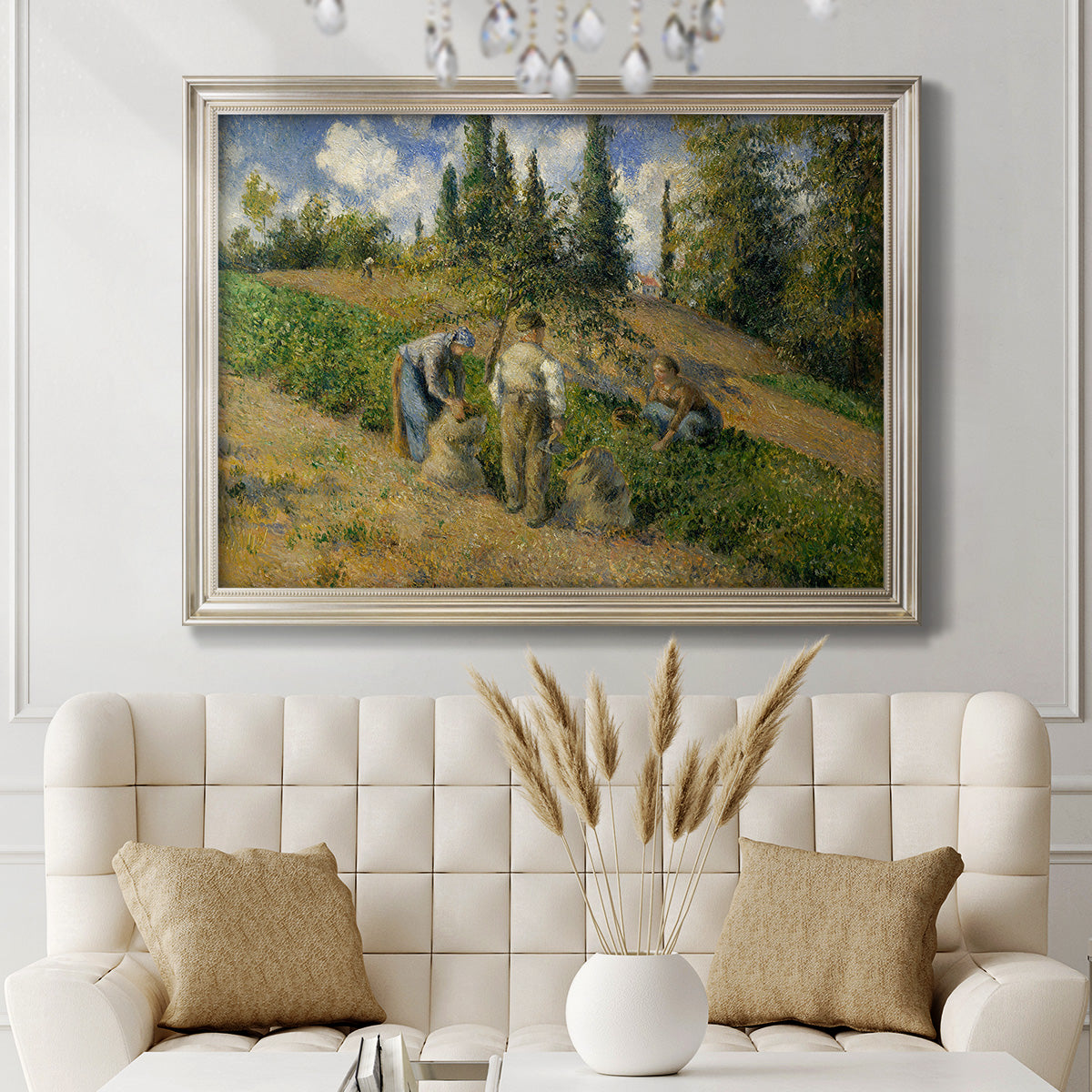 Impressionist countryside harvest scene by Camille Pissarro in an ornate champagne frame displayed in a neutral-toned interior setting.
